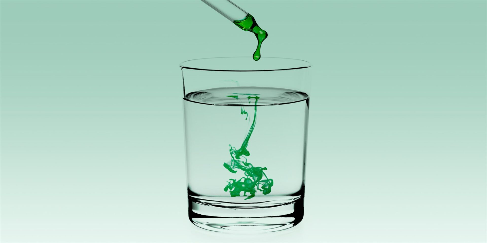 Green liquid dropped on a glass of water