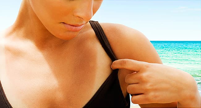 A woman looking at her tan line on the beach