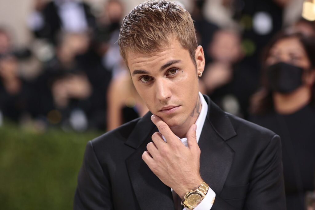 Justin Bieber wearing a black suit and gold watch